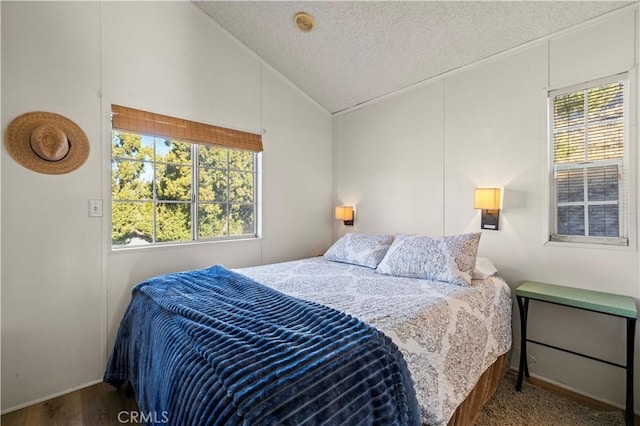 bedroom featuring dark wood-type flooring, a textured ceiling, and vaulted ceiling