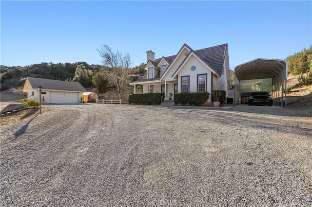 cape cod home with a porch, a garage, an outbuilding, and a carport