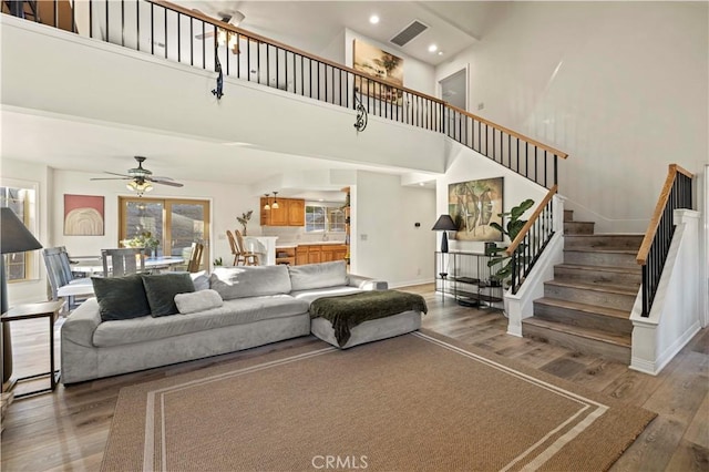 living room with ceiling fan, a towering ceiling, and dark hardwood / wood-style floors