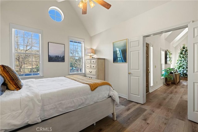 bedroom with ceiling fan, multiple windows, wood-type flooring, and high vaulted ceiling