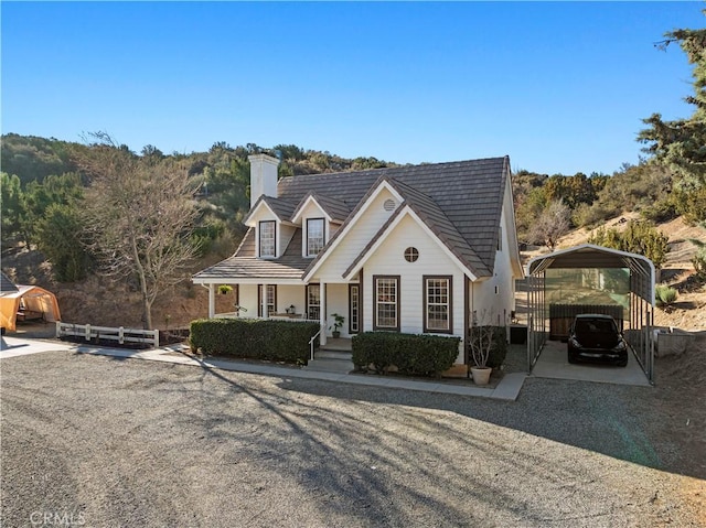 cape cod house featuring covered porch and a carport