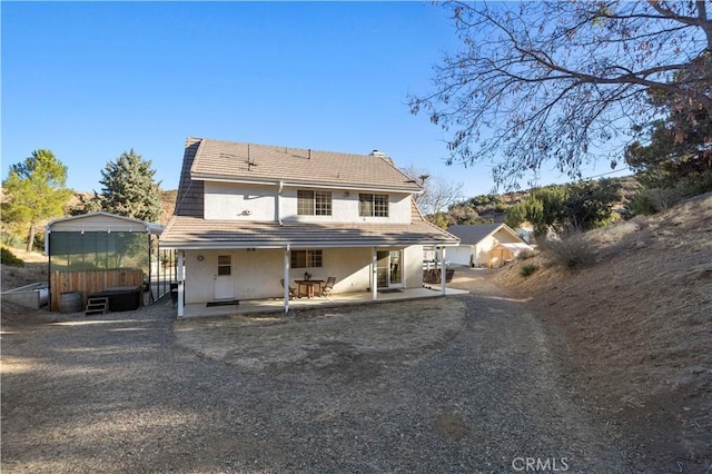 back of house featuring a jacuzzi and a patio