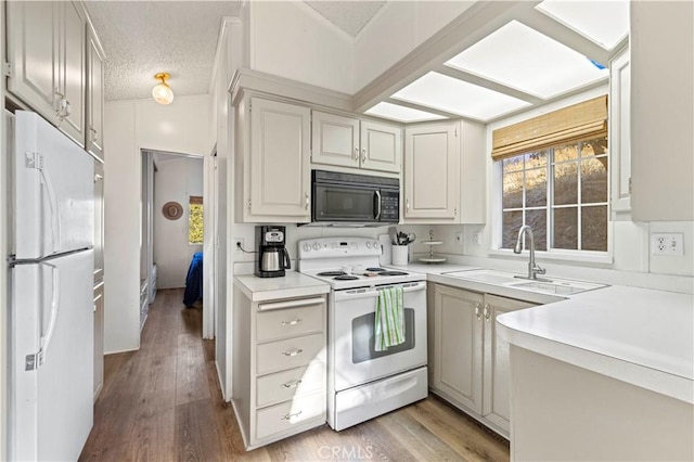 kitchen with a textured ceiling, sink, light hardwood / wood-style flooring, and white appliances