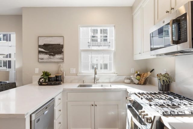 kitchen with white cabinetry, appliances with stainless steel finishes, sink, and kitchen peninsula