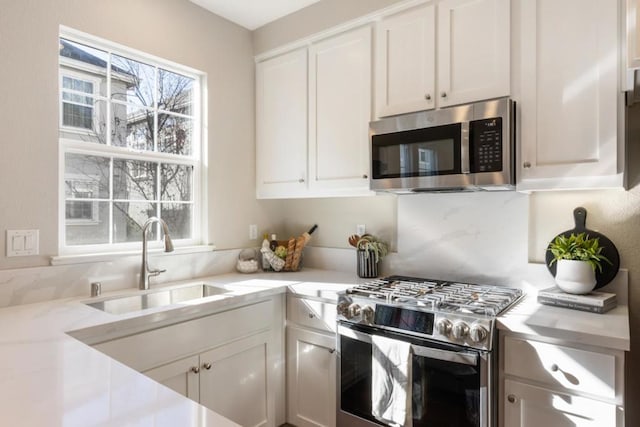 kitchen featuring white cabinetry, stainless steel appliances, light stone countertops, and sink