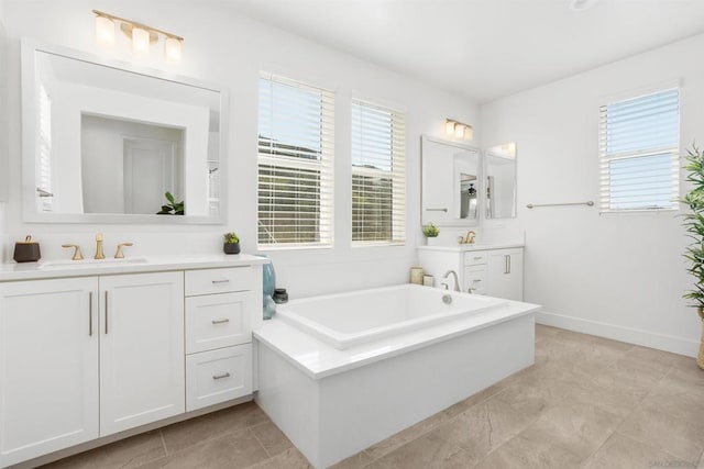 bathroom featuring a healthy amount of sunlight, a washtub, and vanity