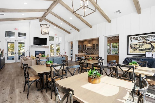 dining space with beamed ceiling, light hardwood / wood-style floors, french doors, and a notable chandelier