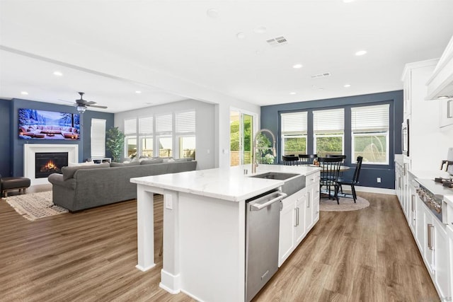 kitchen with white cabinets, appliances with stainless steel finishes, sink, and a center island with sink