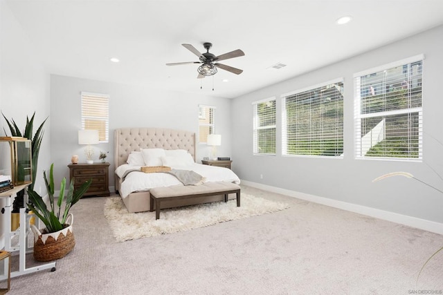 bedroom featuring ceiling fan, light colored carpet, and multiple windows