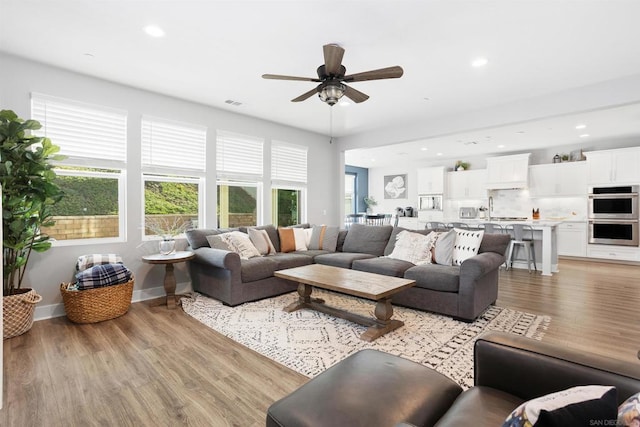 living room featuring ceiling fan, light hardwood / wood-style flooring, plenty of natural light, and sink