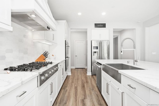 kitchen with custom exhaust hood, backsplash, white cabinets, and light stone countertops