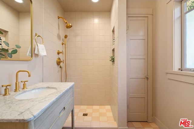 bathroom with tiled shower, a wealth of natural light, and vanity