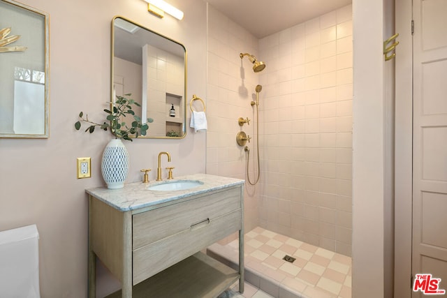 bathroom featuring a tile shower, toilet, and vanity