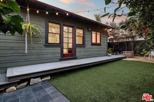 property exterior at dusk featuring a yard and a patio