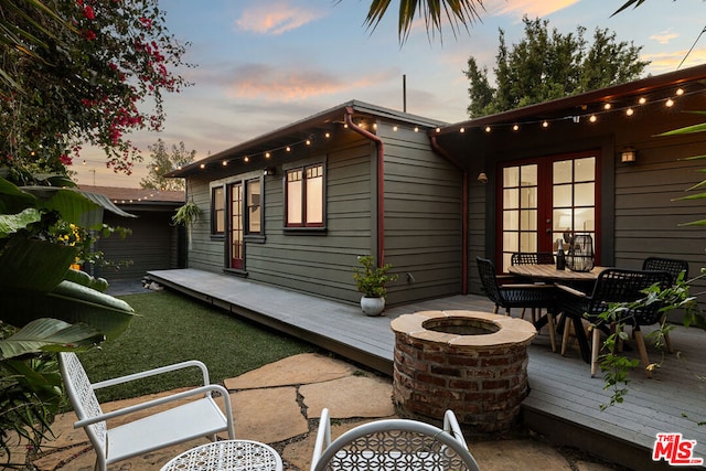 exterior space featuring an outdoor fire pit, a wooden deck, and french doors