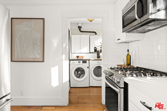 kitchen with white cabinets, light hardwood / wood-style flooring, backsplash, stainless steel appliances, and independent washer and dryer