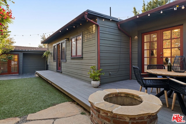 view of side of home with a wooden deck, an outdoor fire pit, and french doors