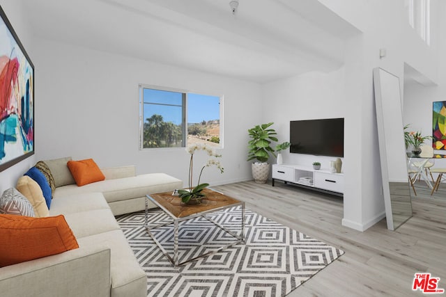 living room with beamed ceiling and light wood-type flooring