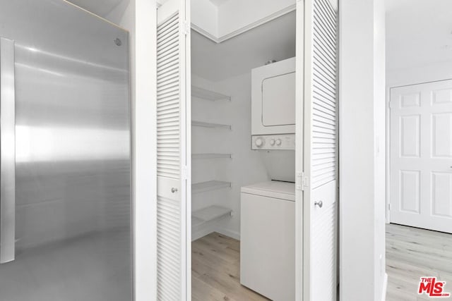 washroom with light wood-type flooring and stacked washer / drying machine