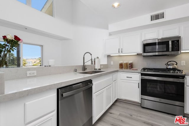 kitchen with tasteful backsplash, white cabinets, sink, and stainless steel appliances