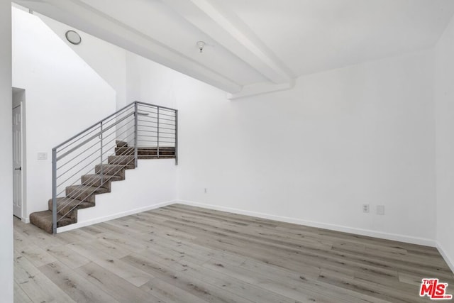 empty room with beam ceiling and wood-type flooring