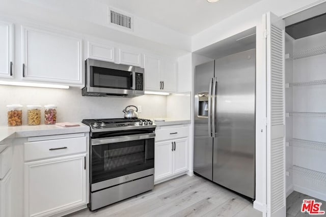 kitchen featuring white cabinets, light wood-type flooring, and stainless steel appliances