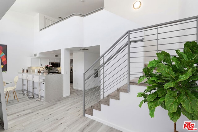 stairs featuring hardwood / wood-style flooring, sink, and a towering ceiling