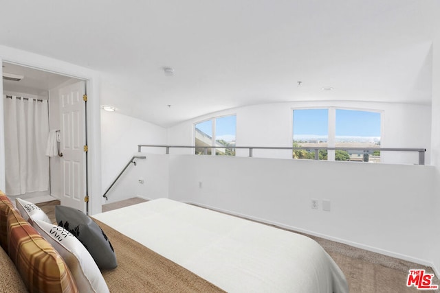 carpeted bedroom with lofted ceiling and multiple windows