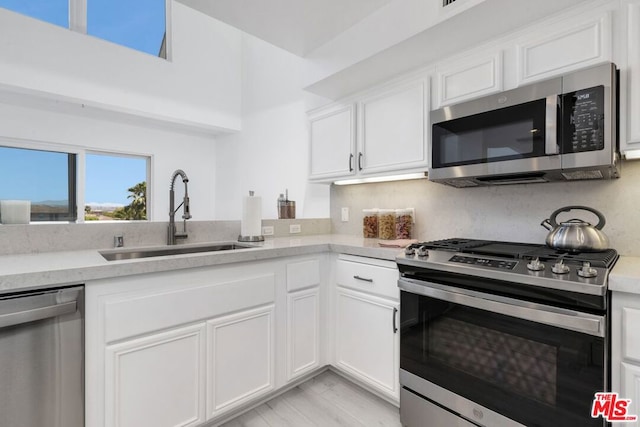 kitchen featuring appliances with stainless steel finishes, white cabinets, and sink