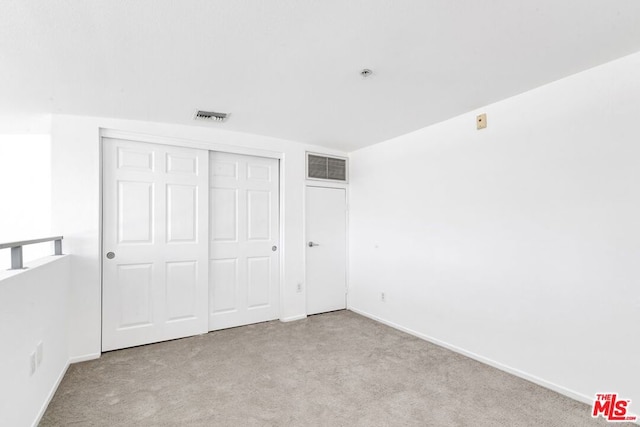 unfurnished bedroom featuring light carpet and a closet