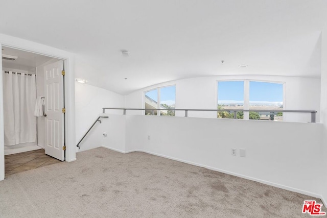 carpeted empty room featuring lofted ceiling