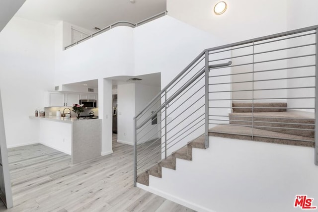 stairway with hardwood / wood-style flooring and a towering ceiling