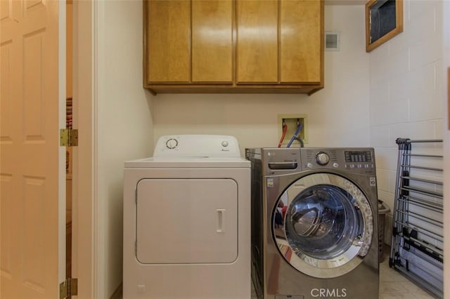 clothes washing area featuring cabinets and independent washer and dryer