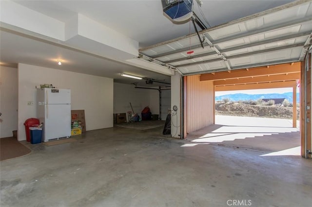 garage with a garage door opener and white refrigerator