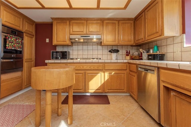 kitchen featuring light tile patterned floors, backsplash, appliances with stainless steel finishes, and tile countertops