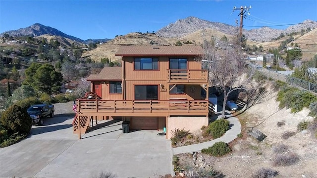 rear view of house featuring a balcony, a deck with mountain view, and a garage