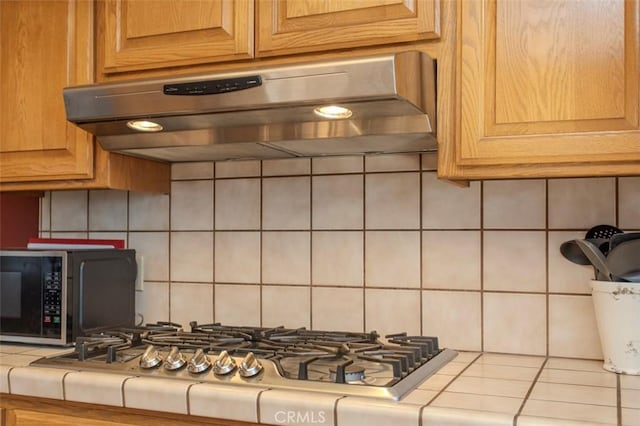 kitchen featuring decorative backsplash, tile countertops, stainless steel gas cooktop, and extractor fan