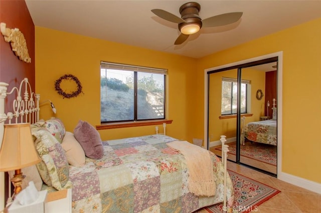 bedroom featuring ceiling fan, light tile patterned floors, and a closet