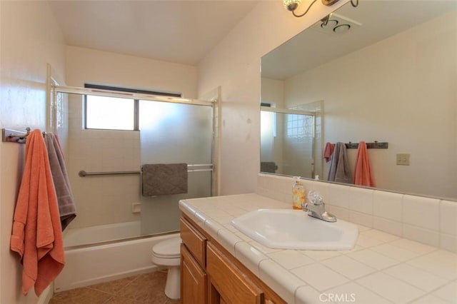 full bathroom featuring toilet, vanity, tile patterned floors, and bath / shower combo with glass door