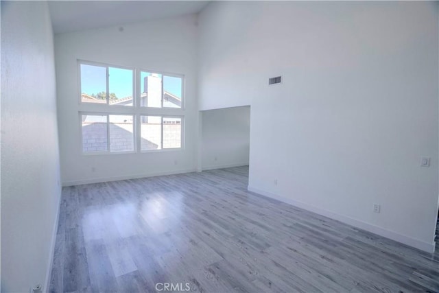 unfurnished room featuring high vaulted ceiling and hardwood / wood-style floors