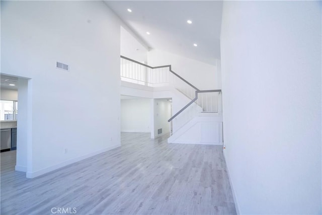 unfurnished living room with light hardwood / wood-style floors and a high ceiling