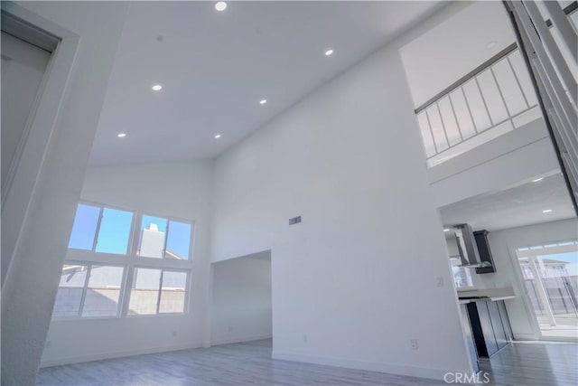 unfurnished living room featuring a healthy amount of sunlight and a high ceiling