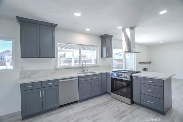 kitchen with island exhaust hood, stainless steel appliances, light hardwood / wood-style floors, sink, and gray cabinets