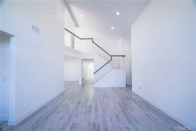 unfurnished living room featuring a towering ceiling and light hardwood / wood-style flooring