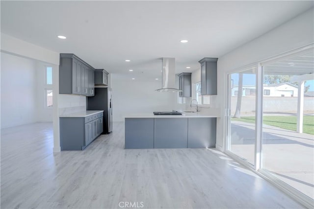 kitchen featuring sink, gray cabinets, ventilation hood, kitchen peninsula, and light hardwood / wood-style flooring