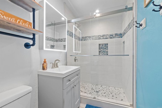 bathroom with walk in shower, vanity, and toilet