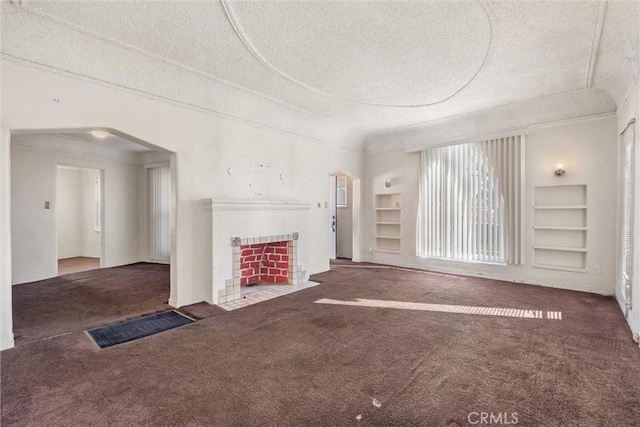 unfurnished living room featuring carpet floors, a textured ceiling, and built in shelves