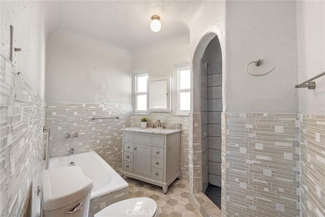 bathroom with a bathing tub, tile walls, vanity, toilet, and tile patterned floors