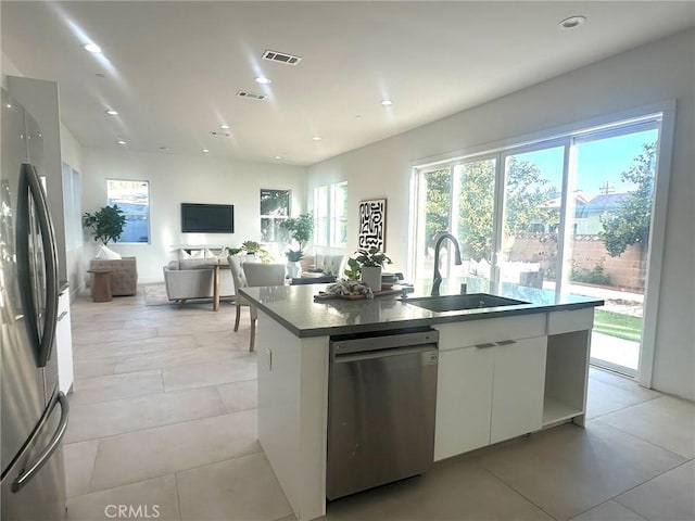 kitchen with sink, stainless steel appliances, white cabinetry, and a kitchen island with sink