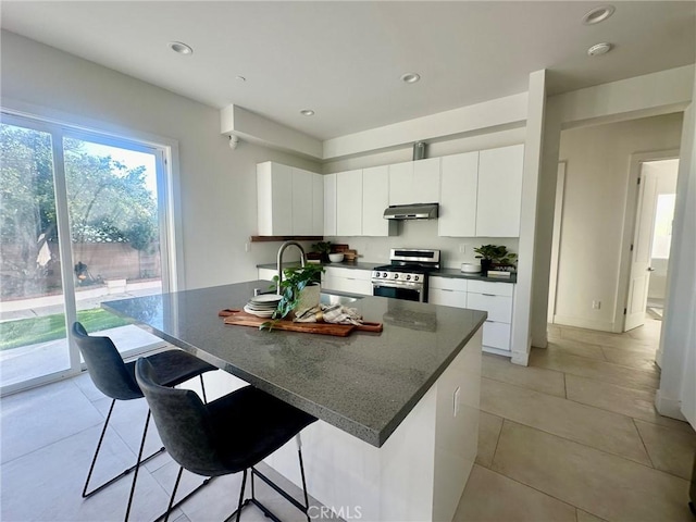 kitchen featuring sink, white cabinetry, stainless steel range oven, a kitchen bar, and a kitchen island